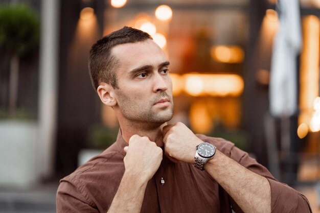 Retrato de um jovem bonito com cerdas não barbeadas em uma camisa marrom corrige o colar