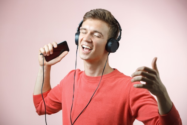 Retrato de um jovem bonito com fones de ouvido, sorrindo e ouvindo uma música