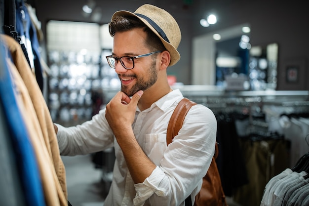 Retrato de um jovem bonito comprando roupas na loja