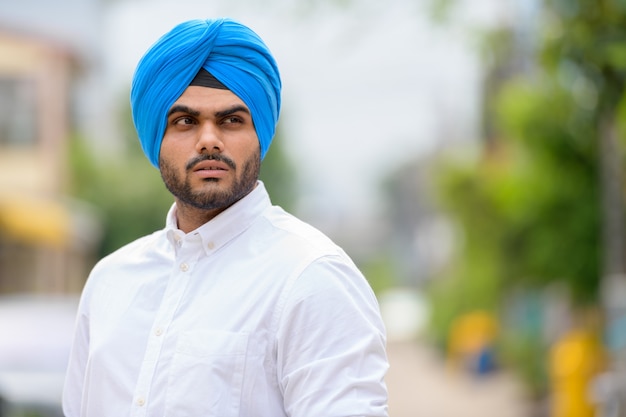 Retrato de um jovem bonito e barbudo indiano Sikh na rua ao ar livre