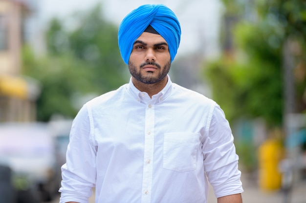 Retrato de um jovem bonito e barbudo indiano Sikh na rua ao ar livre