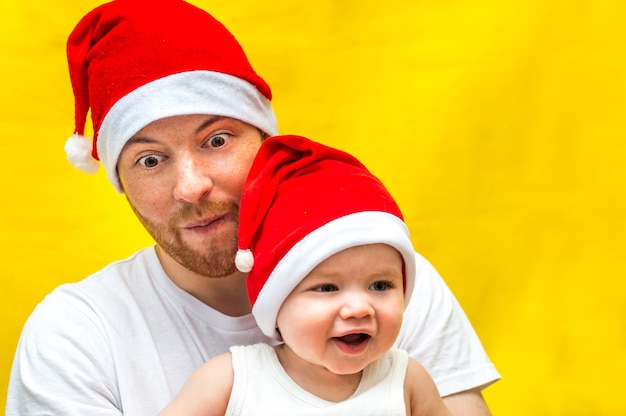 Retrato de um jovem bonito e criança com um chapéu de Papai Noel em amarelo
