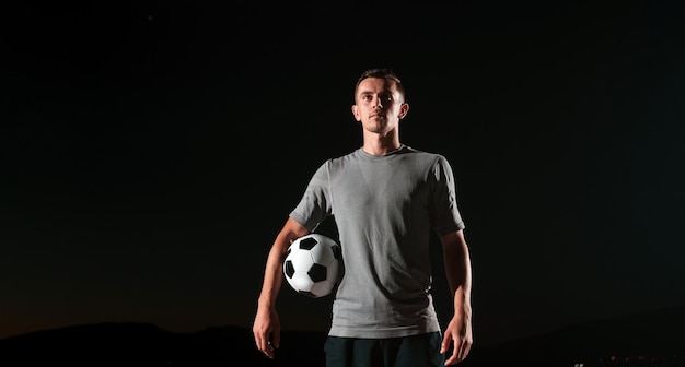 retrato de um jovem bonito e talentoso jogador de futebol em uma rua jogando com uma bola de futebol. foto de alta qualidade