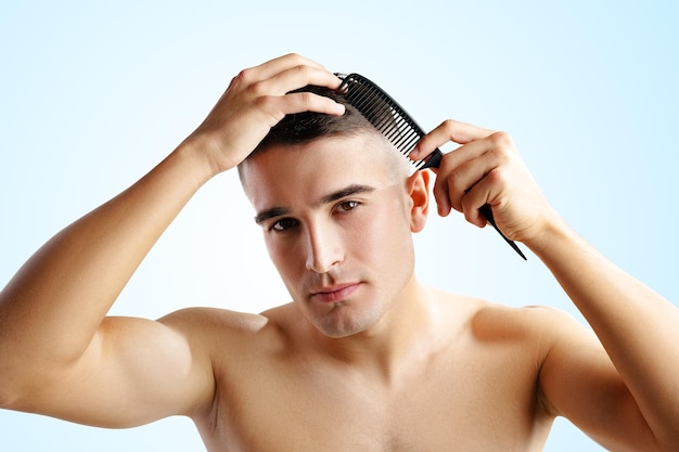 Retrato de um jovem bonito penteando o cabelo em fundo branco