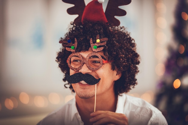 Retrato de um jovem bonito sorridente com máscaras de natal engraçadas.