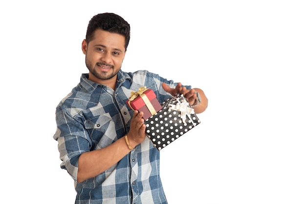 Retrato de um jovem bonito sorridente feliz segurando a caixa de presentes e posando em um fundo branco