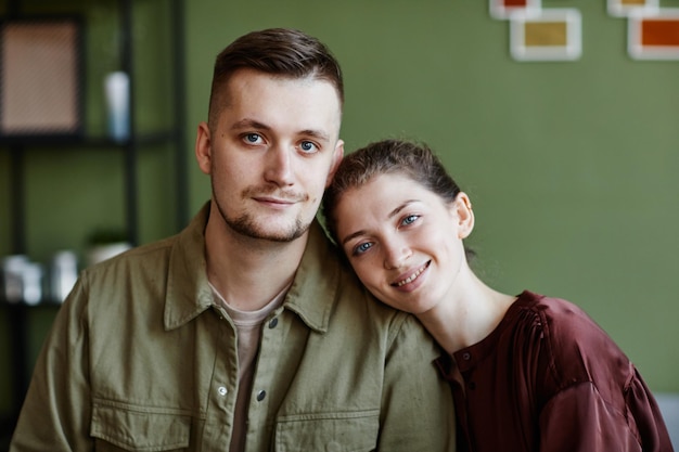 Retrato de um jovem casal adorável sorrindo para a câmera sentado em casa