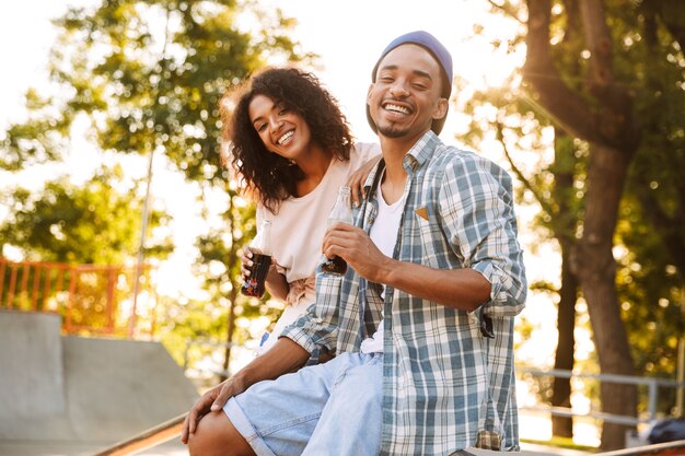 Retrato de um jovem casal africano feliz segurando garrafas