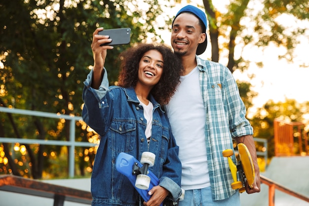 Retrato de um jovem casal africano sorridente com skates