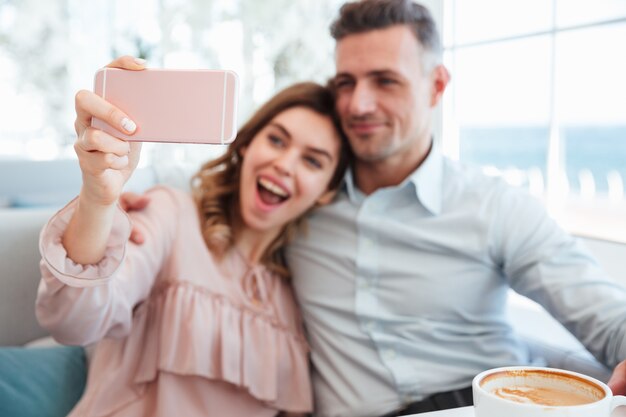 Retrato de um jovem casal alegre, tomando uma selfie