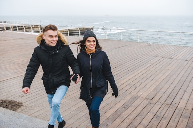 Retrato de um jovem casal amoroso fofo caminhando na praia ao ar livre se divertindo.