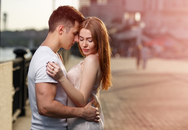 Retrato de um jovem casal apaixonado, apreciando o pôr do sol na cidade.