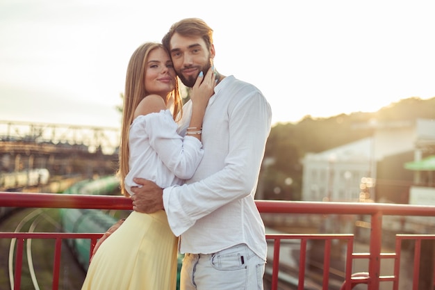 Retrato de um jovem casal apaixonado em um local urbano ao pôr do sol conceito romântico