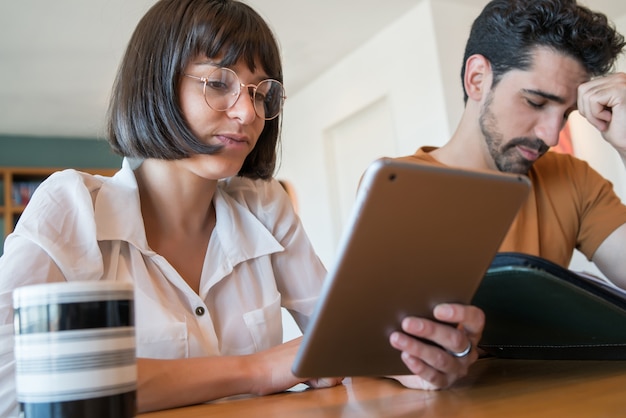 Retrato de um jovem casal calculando e pagando contas em tablet digital a partir de casa. casal planejando orçamento mensal.