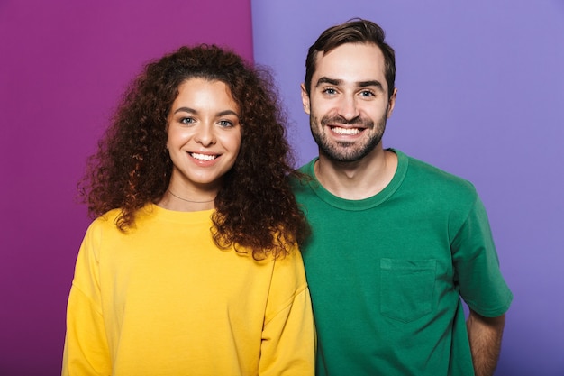 Foto retrato de um jovem casal caucasiano, homem e mulher com roupas coloridas, sorrindo juntos