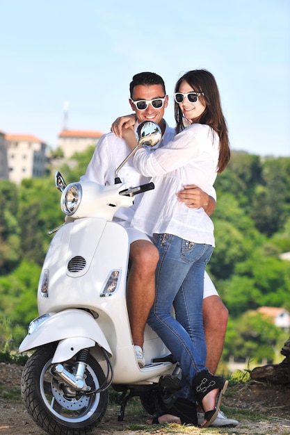 Retrato de um jovem casal de amor feliz na scooter se divertindo em um parque no verão