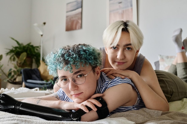 Retrato de um jovem casal de lésbicas olhando para a câmera enquanto passam algum tempo juntos em casa