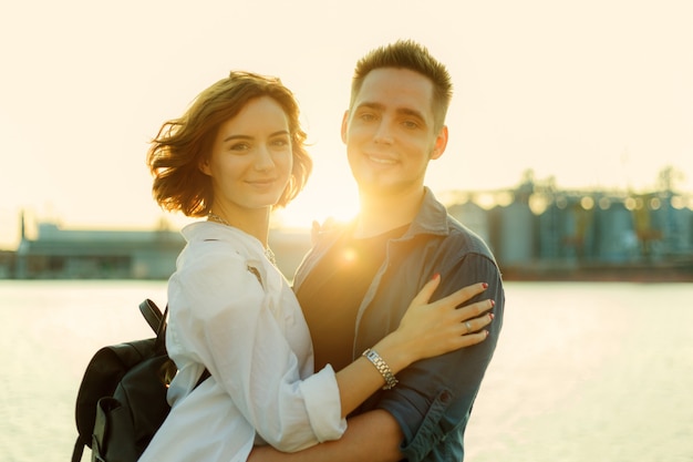 Retrato de um jovem casal de namorados sorridente ao pôr do sol no mar