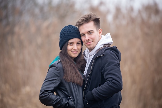 Retrato de um jovem casal em pé na natureza em um dia de inverno