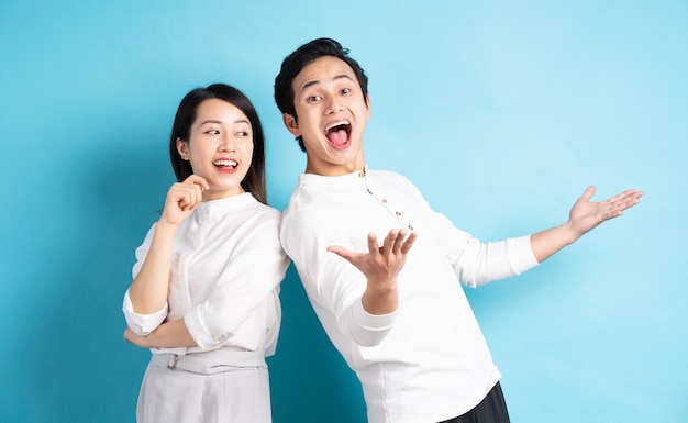 Retrato de um jovem casal em pé, posando na parede azul