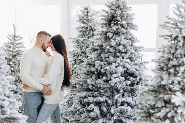 Retrato de um jovem casal em sua sala de estar perto da árvore de natal