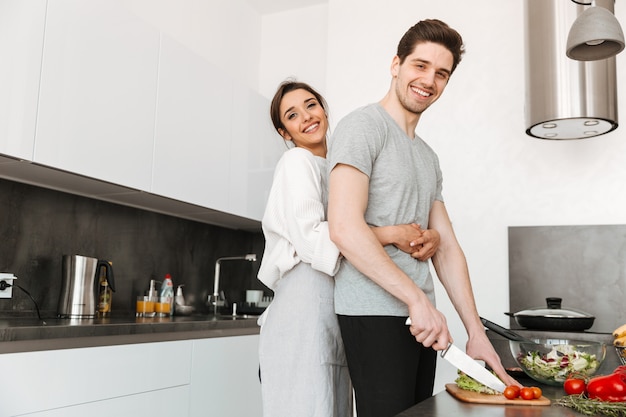 Retrato de um jovem casal feliz, cozinhando juntos