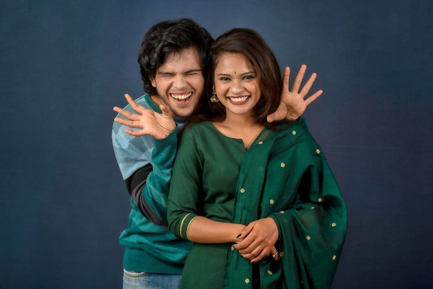 Retrato de um jovem casal feliz e alegre posando em fundo escuro homem e mulher atraentes sendo brincalhões