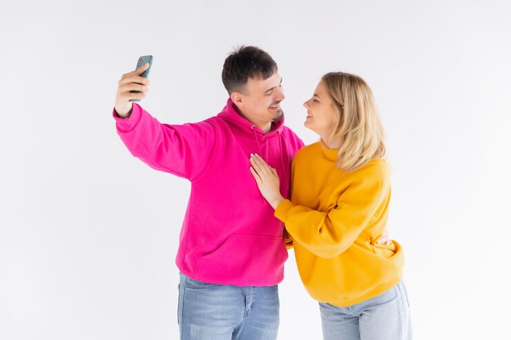 Foto retrato de um jovem casal feliz mostrando os polegares enquanto tomava uma selfie juntos