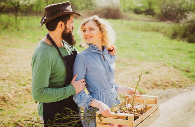 Retrato de um jovem casal feliz no quintal durante a estação de primavera Casal de agricultores Casal de fazendeiros plantando brotos no jardim Família de trabalhadores rurais