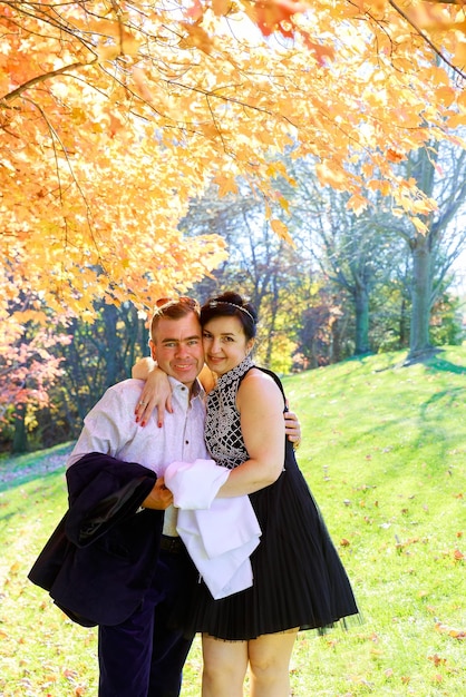 Retrato de um jovem casal feliz vestindo camisas se divertindo ao ar livre perto da cerca no parque