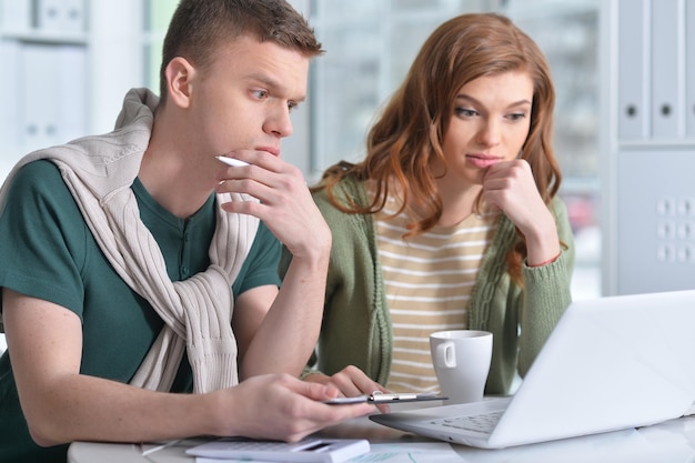 Retrato de um jovem casal lindo com um laptop