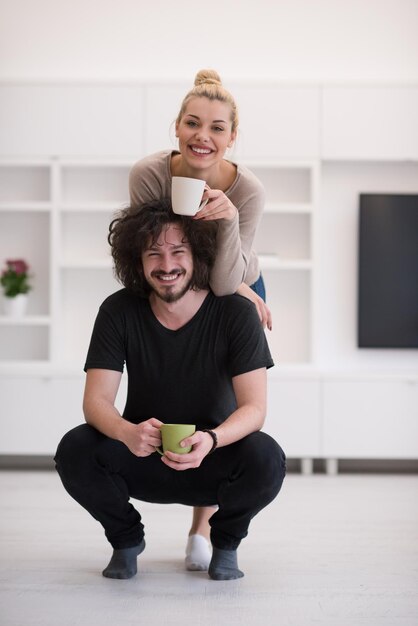 Retrato de um jovem casal lindo feliz abraçando e bebendo café em sua nova casa