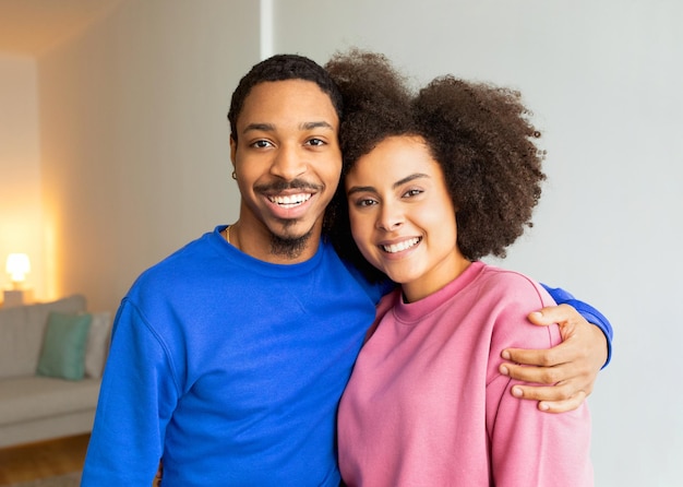 Retrato de um jovem casal negro alegre abraçando-se dentro de casa