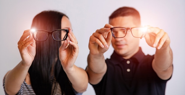 Retrato de um jovem casal olhando através de óculos isolados no branco. Apresentando espetáculos