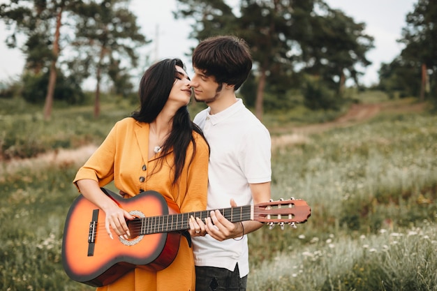 Retrato de um jovem casal romântico cantando violão na natureza. lindo casal jovem olhando um para o outro antes de se beijar.