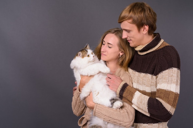 Retrato de um jovem casal segurando um gato persa