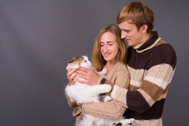 Foto retrato de um jovem casal segurando um gato persa