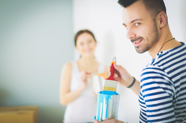 Retrato de um jovem casal sorridente feliz pintando a parede interior da casa nova jovem casal