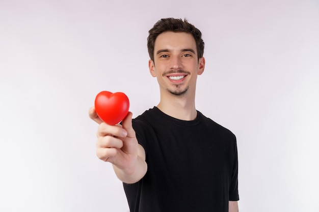 Retrato de um jovem caucasiano feliz vestindo camiseta preta está segurando uma maçã vermelha em fundo isolado