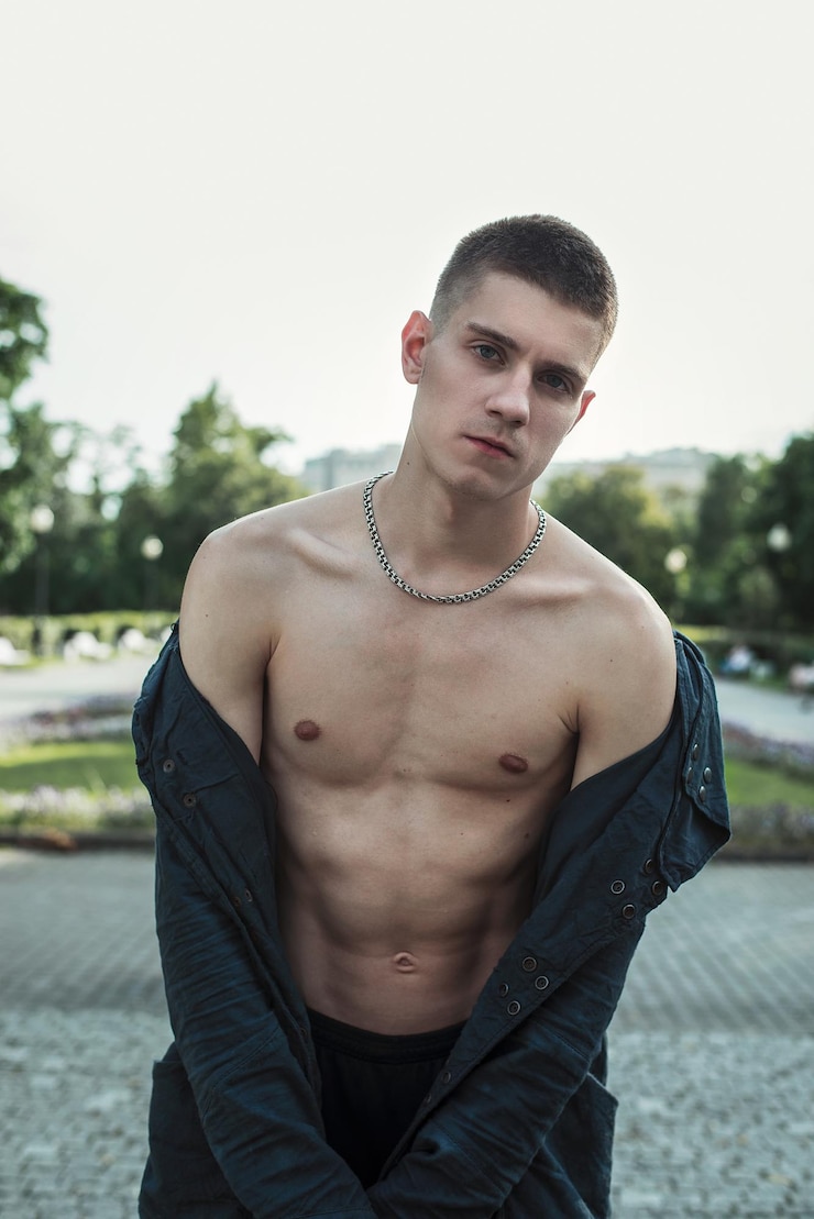 Foto retrato de um jovem com a camisa totalmente desabotoada no parque
