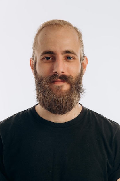 Foto retrato de um jovem com barba em uma camiseta preta em um hipster de fundo branco