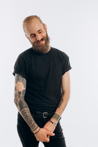 Foto retrato de um jovem com barba em uma camiseta preta em um hipster de fundo branco