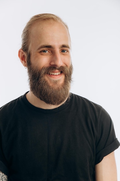 Retrato de um jovem com barba em uma camiseta preta em um hipster de fundo branco