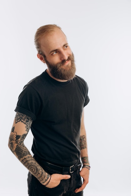 Foto retrato de um jovem com barba em uma camiseta preta em um hipster de fundo branco