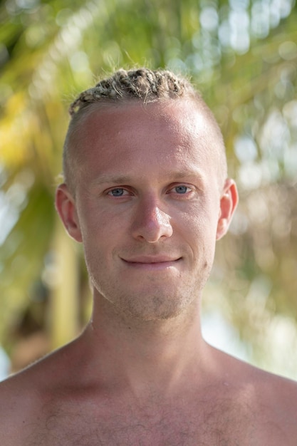 Retrato de um jovem com dreadlocks na cabeça na natureza Homem bonito feliz com dreadlocks na praia tropical close-up