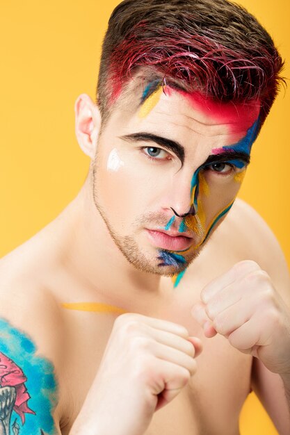 Retrato de um jovem com pintura no rosto colorido sobre um fundo amarelo