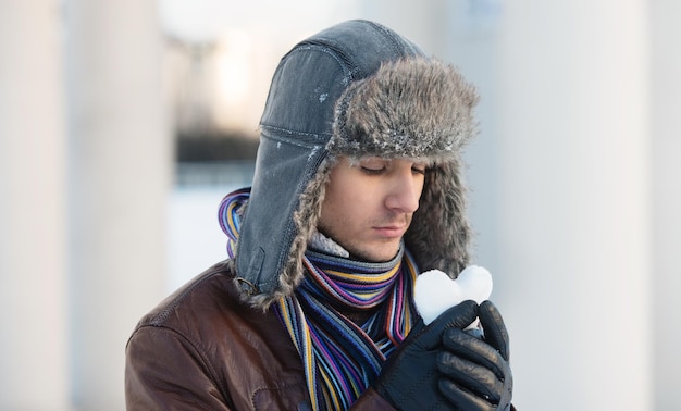 Retrato de um jovem com um chapéu de orelha segurando uma bola de neve em forma de coração