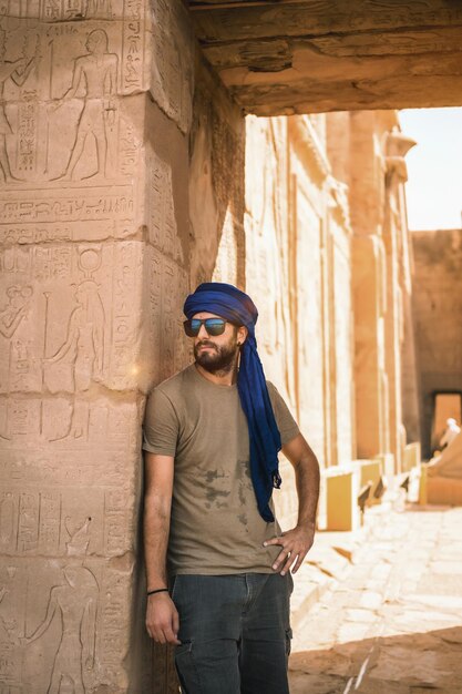 Foto retrato de um jovem com um turbante azul na entrada do templo de edfu