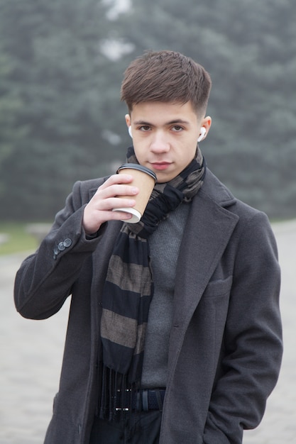 Foto retrato de um jovem com uma xícara de café, clima de inverno nevoento. foto em tons de cinza