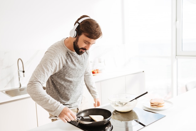 Retrato de um jovem concentrado cozinhar panquecas